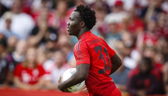 A football player in a blue Chelsea jersey, possibly Madueke, gestures with his hands during a match against Arsenal, looking frustrated.