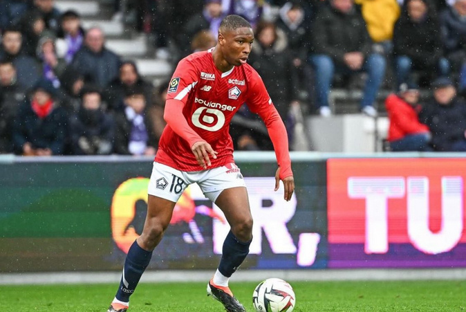 Sunderland player in a red jersey controls the ball during a match, with spectators in the background.