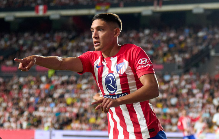 Soccer player in a red and white Nottingham Forest jersey pointing during a match with a crowd in the background.
