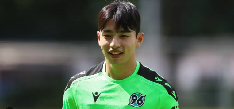 Soccer player in a green jersey with the number 96 logo, smiling outdoors, channels energy reminiscent of Bayern’s Lee Hyun-ju.