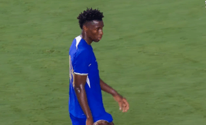 Chelsea player Nicolas Jackson in a blue jersey walking on the grass field during a game.