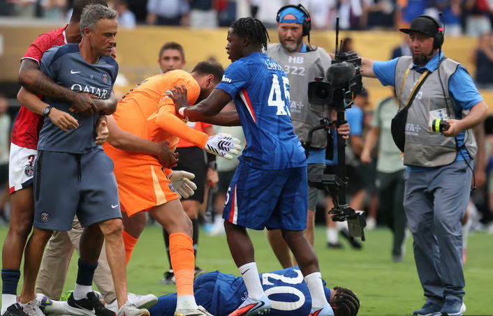 Soccer players and staff, including PSG’s Luis Enrique, crowd around a player on the ground during an intense Club World Cup moment on the field.