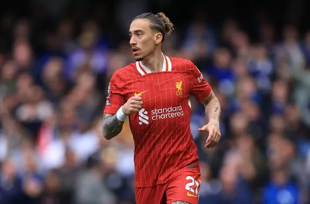 Greek defender Tsimikas, in a red Liverpool kit, runs on the field during a match.
