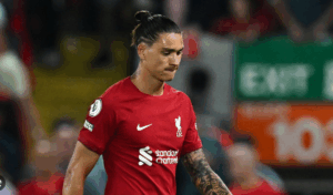 A football player in a red Liverpool jersey, No. 9 Nunez, looks down during a match, background blurred.