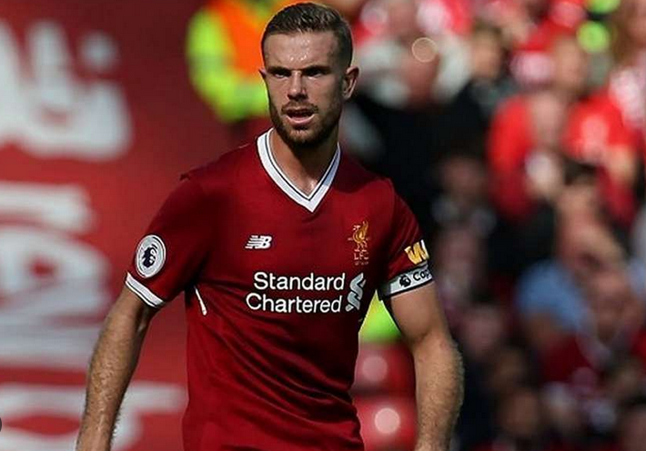 Liverpool’s Henderson, in a red jersey, controls the ball on the field during a Champions League match against Brentford.