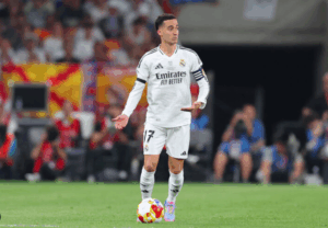 Lucas Vazquez, in his white Real Madrid uniform, stands on the field with the ball at his feet during a match, marking his 400-match milestone for the club.