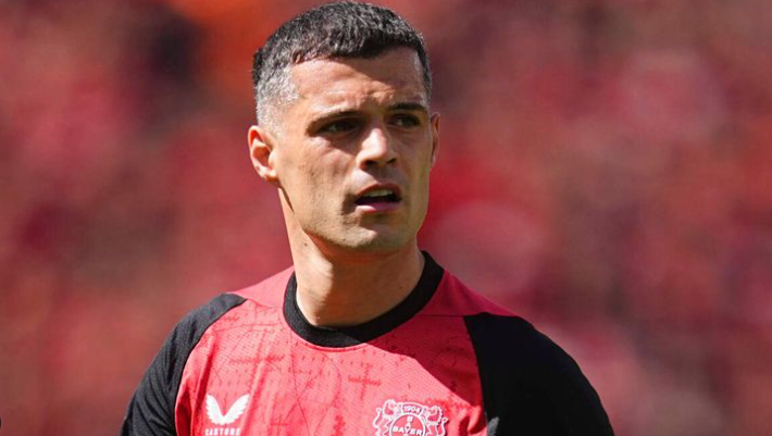 A male soccer player in a red and black jersey stands on the field, looking to the side, reminiscent of Sunderland’s iconic colors during their Premier League return.
